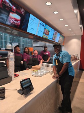 Five people from the Hoover Qdoba crew standing behind the counter